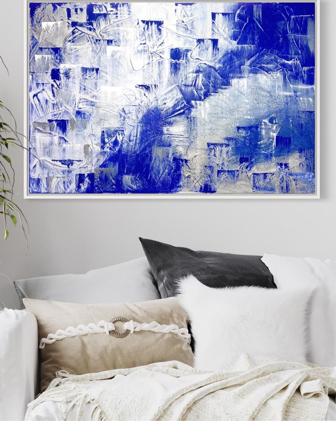 Arctic Dream, a blue, white, and silver layered abstract painting by Julia Mindar, framed above a bed