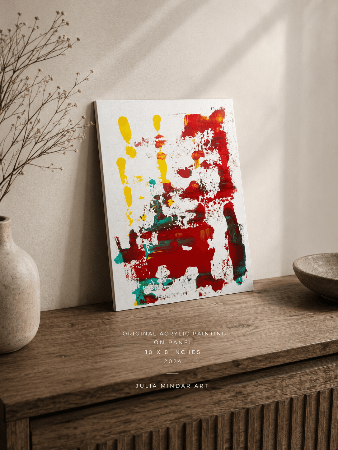 Ignition, a small red, yellow, and teal abstract painting by Julia Mindar, leaning on a wood console