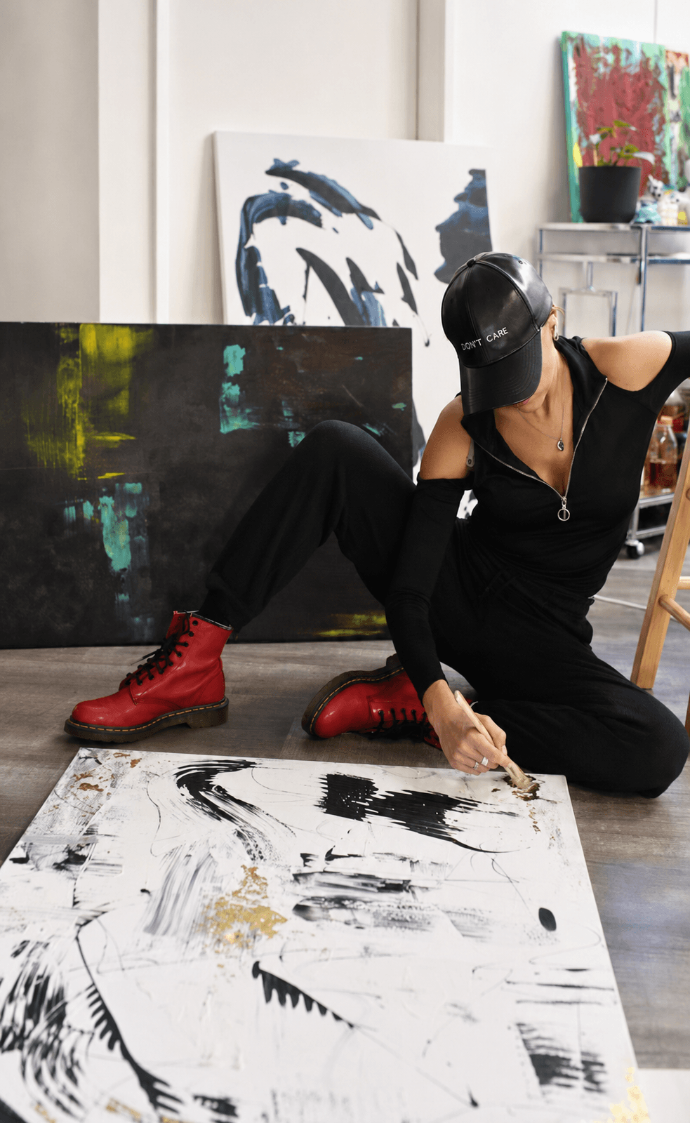 Julia Mindar working on a black, white, and gold leaf painting in her Los Angeles studio