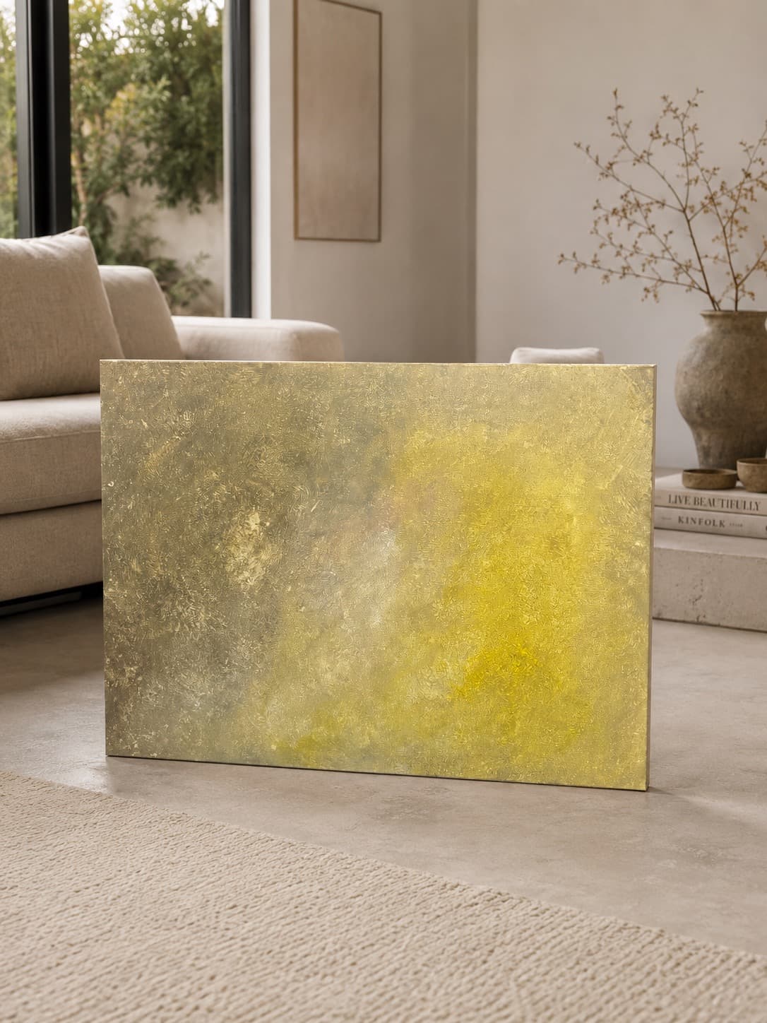 Golden Haze, a soft gold, warm yellow, and muted gray abstract painting by Julia Mindar, shown above a sofa